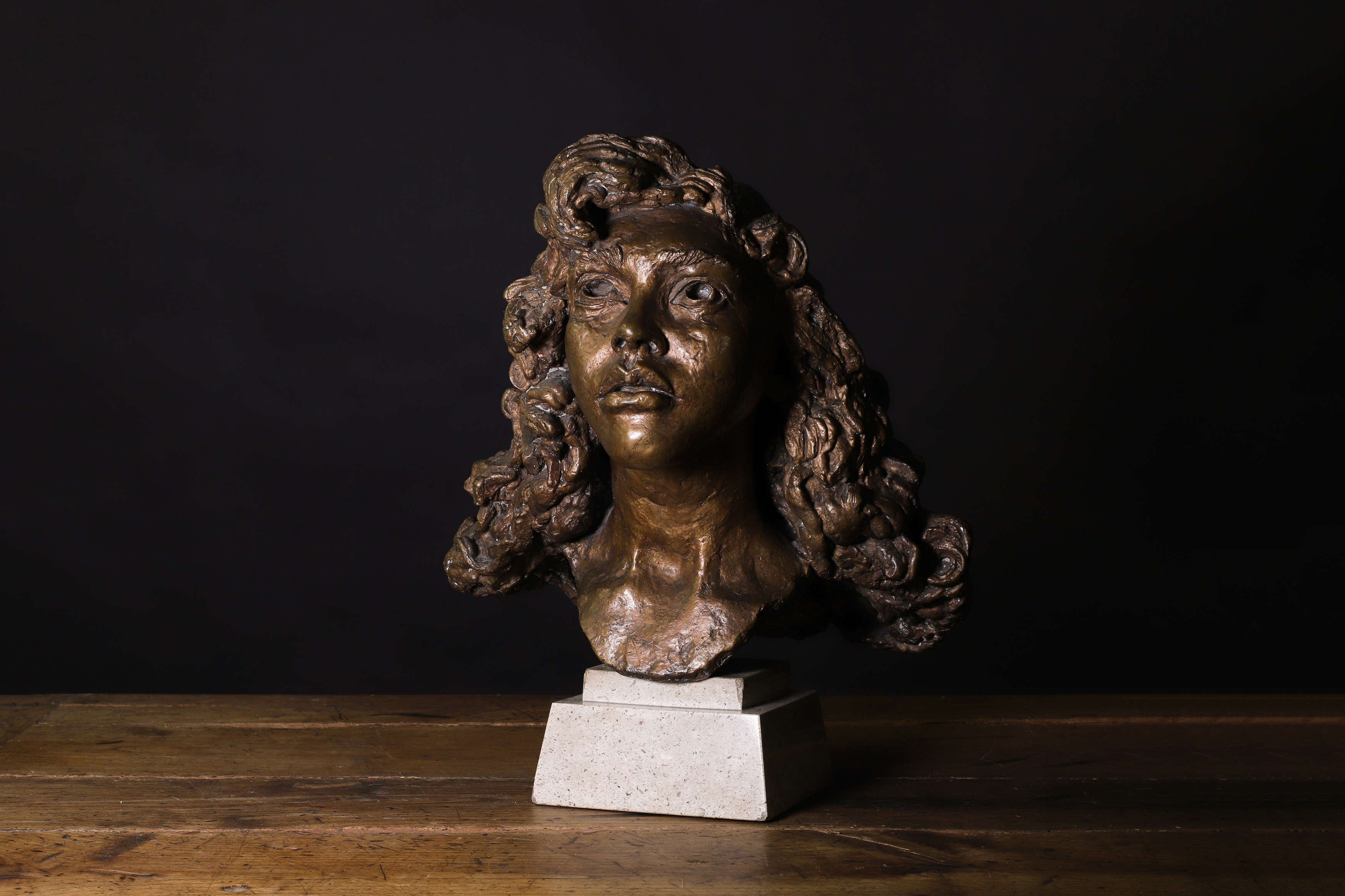 Sir Jacob Epstein (1880-1959) First portrait of Kitty (with curls) bronze with a gold-brown patina, conceived in 1944 42cm wide 43cm deep 47cm high overall, on a composite stone base (£6,000-7,000)