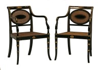 Lot 21 - A pair of reproduction Regency-style ebonised elbow chairs