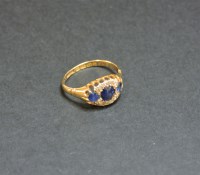 Lot 29 - An 18ct gold three stone sapphire and diamond cluster ring