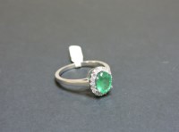 Lot 49 - An 18ct white gold emerald and diamond oval cluster ring
