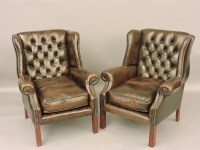 Lot 789 - A pair of brown leather button back wing armchairs