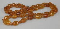 Lot 1048 - A single row graduated faceted olive shaped amber bead necklace