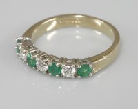 Lot 1006 - A 9ct gold emerald and diamond half eternity ring