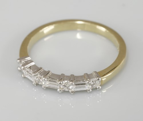 Lot 1016 - An 18ct yellow and white gold baguette cut diamond and brilliant cut diamond half eternity ring