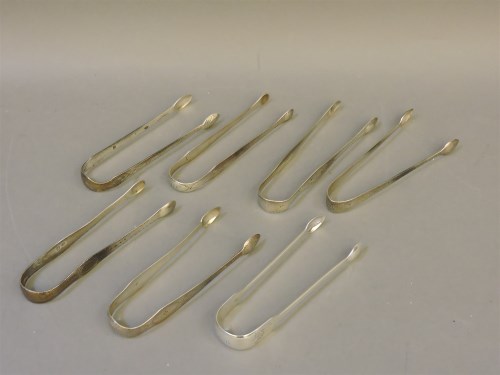 Lot 1127 - Seven George III silver bright cut sugar tongs