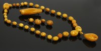 Lot 379 - A graduated egg yolk amber bead necklace and pendant