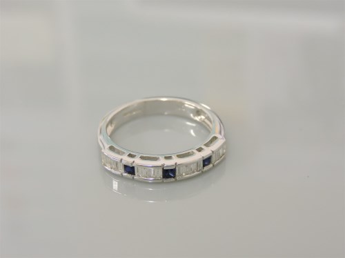 Lot 21 - An 18ct white gold sapphire and baguette cut diamond half eternity ring