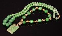 Lot 449 - A jade bead gold bracelet with a carved jade pendant