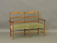 Lot 460 - An Arts and Crafts oak two seater ladder back settee