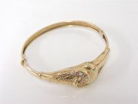 Lot 23 - A gold ruby and white stone scroll centrepiece hinge bangle