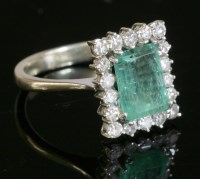 Lot 572 - A white gold emerald and diamond rectangular cluster ring