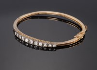 Lot 385 - A cased Edwardian diamond set hinged bangle