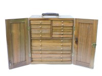 Lot 197 - A wooden two door cabinet with drawers of coins