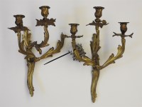 Lot 431 - A set of four gilt metal (Ormalu) three branch candle sconce wall lights