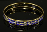 Lot 1004 - An Hermès narrow blue enamel gold-plated bangle