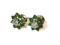 Lot 1007 - A pair of gold illusion set diamond and emerald cluster earrings