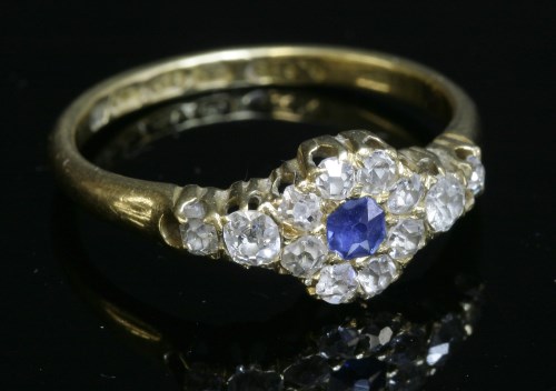 Lot 52 - An 18ct gold sapphire and diamond cluster ring with diamond set shoulders