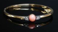 Lot 110 - An Edwardian coral and diamond set hinged gold bangle