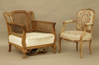 Lot 564 - An early 20th century walnut bergere chair with carved arms and on paw feet