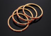 Lot 402 - A set of four high carat gold Indian coral and cultured pearl bangles