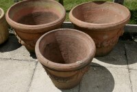 Lot 1056 - A pair of large terracotta pots decorated with fruiting swags 60cm diameter together with a matching smaller pot