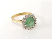 Lot 1023 - A gold circular emerald and diamond cluster ring