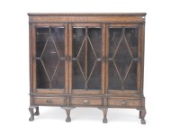 Lot 497 - An oak bookcase with three sliding glazed doors