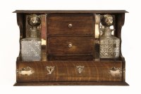 Lot 92 - An early 20th century two bottle tantalus with two decanters flanking three small drawers