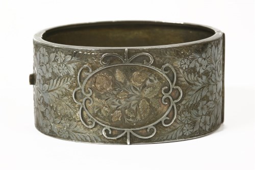 Lot 1022 - A Victorian silver hinge bangle with floral scrolling decoration on top section