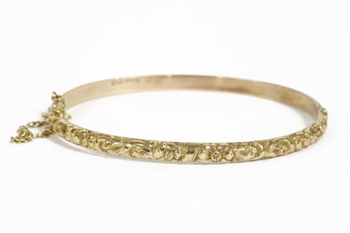 Lot 38 - A 9ct gold hinged bangle with repoussé top section