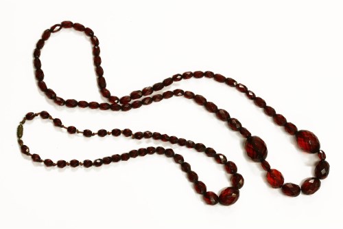 Lot 89 - A single row graduated faceted cherry coloured early plastic bead necklace