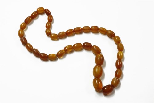 Lot 86 - A single row graduated olive shaped amber bead necklace