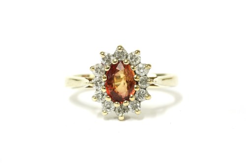 Lot 23 - A 9ct gold orange sapphire and diamond cluster ring