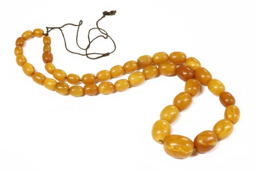 Lot 34 - A single row graduated olive shaped amber bead necklace