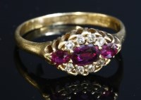 Lot 101 - An 18ct gold three stone ruby and diamond oval cluster ring