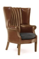 Lot 642 - A Georgian style leatherette upholstered barrel backed wing armchair on square tapering legs