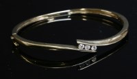 Lot 422 - A 9ct gold three stone diamond crossover hinged bangle