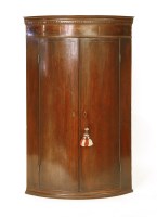 Lot 531 - A Georgian mahogany and inlaid bow front corner cupboard