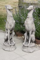 Lot 617 - A pair of cast stone garden sculptures of whippets seated on octagonal bases