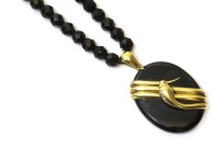 Lot 326 - An onyx locket suspended on a single row faceted glass bead necklace
