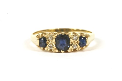 Lot 147 - An 18ct gold carved head three stone sapphire ring