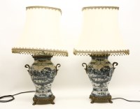 Lot 224 - A pair of blue and white porcelain table lamps with chinoiserie decoration on gilt metal paw feet