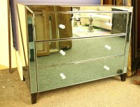 Lot 384 - A mirrored glass three drawer chest on ebonised block feet