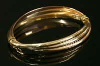 Lot 383 - An Italian three colour gold hollow Russian wedding ring style hinged bangle