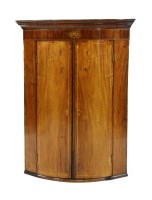 Lot 651 - A George III bowfront mahogany corner cupboard