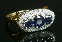 Lot 401 - An 18ct gold three stone sapphire and diamond, landscape, oval cluster ring
