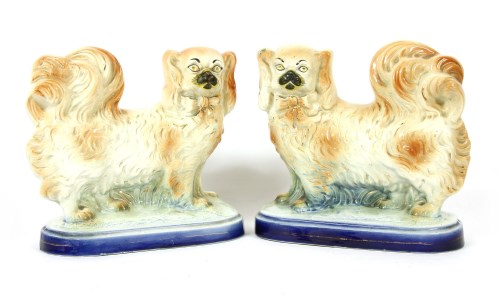 Lot 309 - A mirrored pair of late 19th to early 20th century Staffordshire figures depicting standing Pekingese dogs