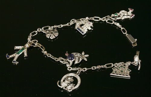 Lot 488 - A white gold Art Deco style sapphire, emerald, ruby and diamond set charm bracelet