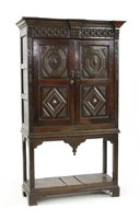 Lot 714 - An oak and inlaid cupboard on stand