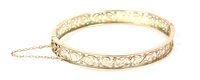 Lot 76 - A gold pierced oval hinged flat section bangle